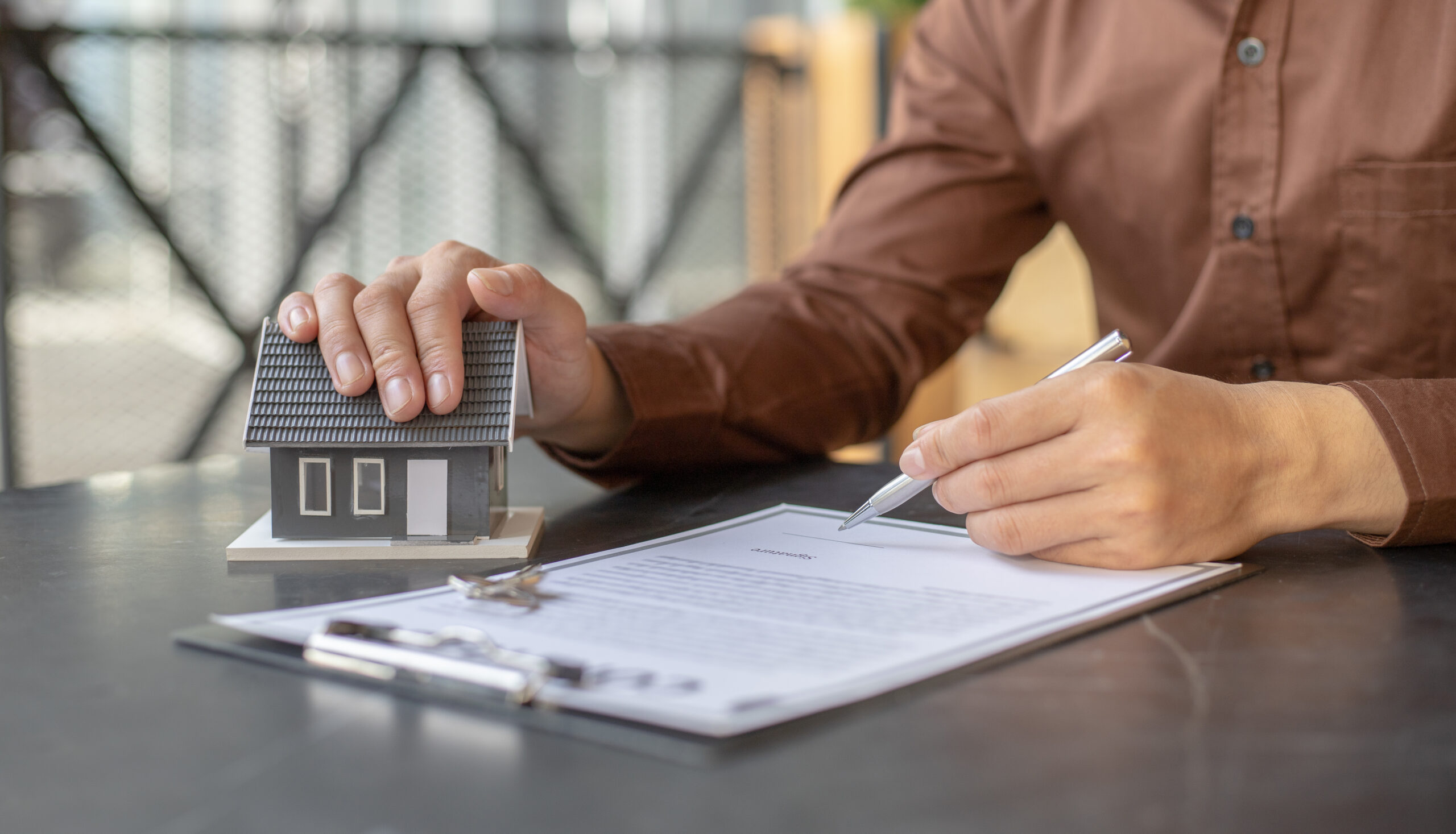 Sales manager or real estate agent prepares to hand over the keys and the house together with the insurance to the customer, Attention to property services and insurance concept.